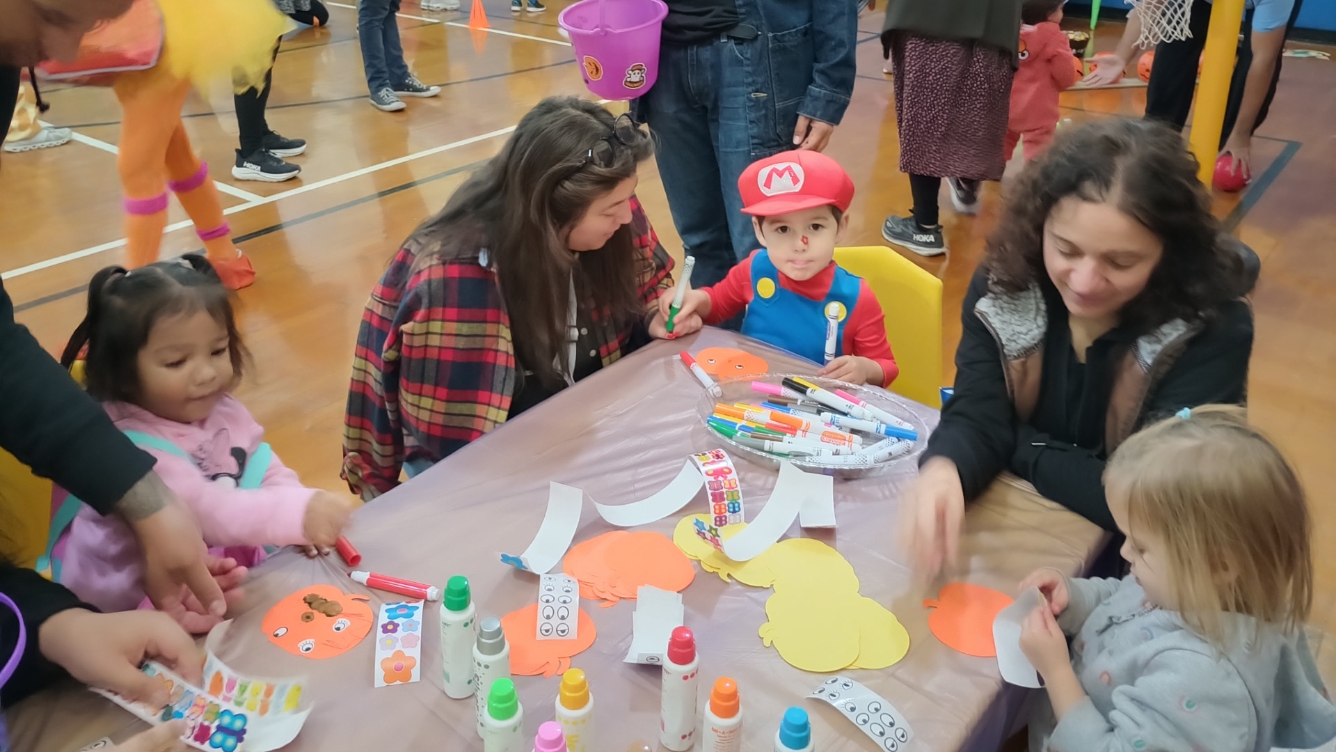 Halloween carnival with kids crafting at a table.